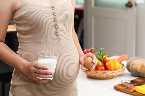 Ibu hamil memegang susu dan telur